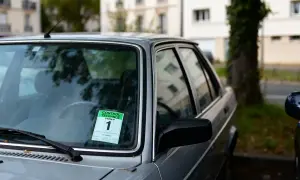 Autocollant vert sur le pare-brise d'une voiture indiquant "Contrôle technique périmé 1 mois".