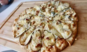 En utsökt pizza med päron, valnötter och krämig gorgonzola på en träskärbräda.