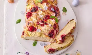 Ein köstlicher Osterzopf mit Quark und Beeren, bestäubt mit Puderzucker und verziert mit Minze und kleinen Blüten.