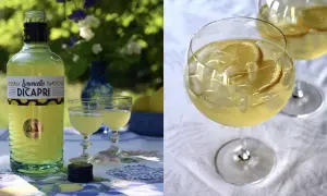 En flaska Limoncello Di Capri står bredvid två glas med drinken. Två glas med is och citroner fyller högra sidan. En perfekt limoncello spritz för en solig dag.