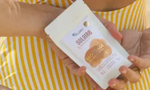 Une main tient un paquet de "Solaire Bronzage" de Valebio, suggérant une peau protégée et hâlée.