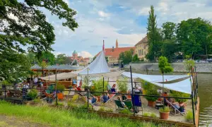 Entspannte Atmosphäre an einem Flussufer-Café in Breslau. Ein perfekter Ort für Breslau Geheimtipps, mit Liegestühlen und Sonnensegeln.