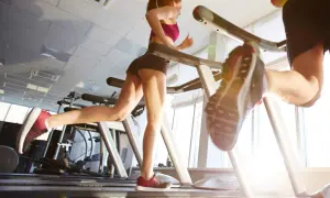 Due persone corrono sui tapis roulant in palestra. Nonostante correre fa venire la cellulite, loro si allenano con determinazione.
