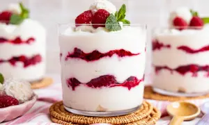 Raffaello-Dessert im Glas mit Himbeeren und Kokosflocken, garniert mit Minze.