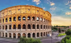 Colosseum i Rom, en ikonisk gammal stad i Italien, badar i gyllene solljus. Turister promenerar på torget framför den imponerande amfiteatern.