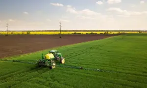 Zielony traktor z opryskiwaczem na polu, przygotowuje się do ochrony upraw przed szkodnikami, jak afalon.