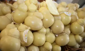 Un cesto pieno di formaggio podolico, alcuni a forma di pera, legati con spago. Un pezzo di formaggio è appoggiato sopra.