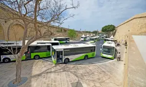 Malta autobusy z lotniska czekają na pasażerów przy zabytkowych murach.