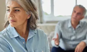 Een vrouw kijkt weg tijdens een gesprek, de man op de achtergrond gebaart. Dit beeld roept de vraag op: wanneer heeft relatietherapie geen zin?
