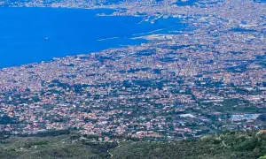 Blick über die weitläufige Stadt Neapel, Italien, mit dem blauen Meer und dem Hafen im Hintergrund.