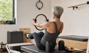 Donna matura con un anello Pilates, impegnata in un allenamento per raddrizzare la schiena a 50 anni.