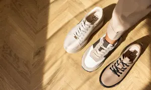 Ciekawe, jakie buty do cygaretek zimą? Na drewnianej podłodze leżą beżowe sneakersy i eleganckie botki.