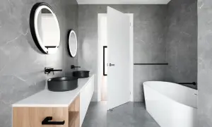 Elegante baño blanco y negro pequeño con lavabos negros, bañera exenta y espejos redondos iluminados.