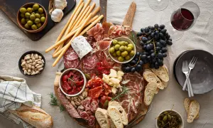 En generös bricka med italienska snacks: charkuterier, oliver, soltorkade tomater, ost, vindruvor, grissini och bröd. Perfekt för en mysig kväll.
