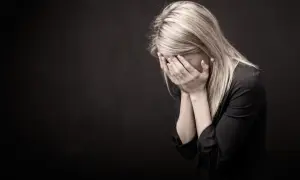 Kobieta zakrywa twarz dłońmi, symbolizując trudności i emocjonalne wyzwania związane z tym, jak złagodzić skutki odstawienia antydepresantów.