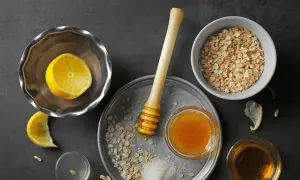Zutaten für ein natürliches Peeling zur Hautentgiftung: Haferflocken, Honig, Zitrone und Zucker.