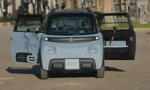 Citroën Ami 100% Electric, in prova, con portiere aperte e grafica stilizzata.