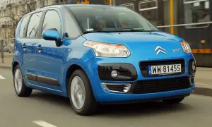 Niebieski Citroen C3 Picasso 2009 jedzie ulicą, mijając tramwaj.