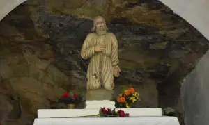 Kamienna grota, w której 13 lipca stoi figura świętego w zniszczonym habicie. Obok kwiaty.