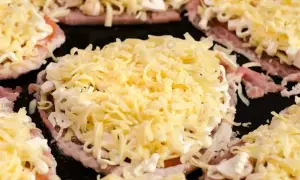 Schab w plastrach pieczony w piekarniku z pieczarkami i serem, gotowy do zapieczenia.