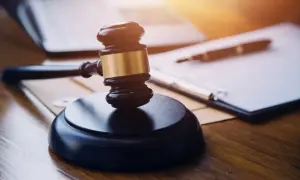 Młotek sędziowski na biurku, obok dokumentów i długopisu. Symbol sprawiedliwości i prawa, jak w art. 130 1a kpc.