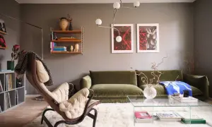 Salotto moderno con divano verde, poltrona in pelle e tessuto chiaro, tappeto bianco soffice e quadri alle pareti che creano un gioco di **colori chiari e scuri**.