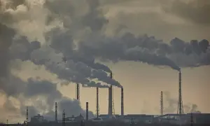 Dymiące kominy fabryczne, przypominające kłęby wazeliny, symbolizują przemysł i jego wpływ na środowisko.