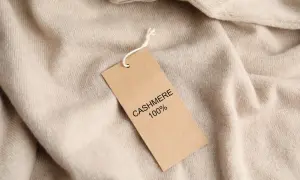 Ein Etikett auf einem beigefarbenen Pullover erklärt, woraus Kaschmir besteht: 100% Kaschmir.