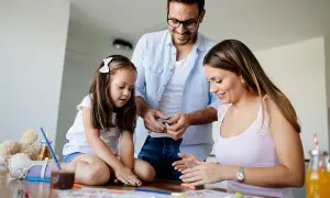 Familia feliz disfrutando de una **actividad día de la familia**, creando arte con plastilina y colores.