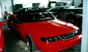 En röd Saab 9000 cabriolet står i ett garage, redo för en tur.