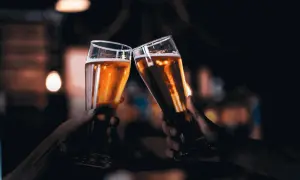 Due mani brindano con due bicchieri di birra dorata, un gesto che nasconde un'intolleranza alla birra.