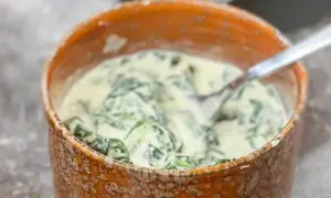 Creamy spinach in a rustic bowl with a fork.