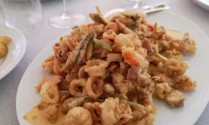 Un piatto invitante di frittura di paranza, con calamari, gamberi e pesciolini dorati e croccanti.