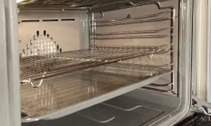 Wnętrze piekarnika z rusztami i blachą, gotowe do czyszczenia katalitycznego.