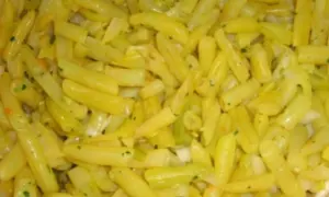 Nahaufnahme von gekochten gelben Bohnen, gewürzt mit Kräutern und Zwiebeln. Ein leckeres Gericht mit gelben Bohnen.