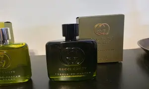 Dwie butelki perfum Gucci Guilty na ciemnym tle, jedna z nich z pudełkiem.