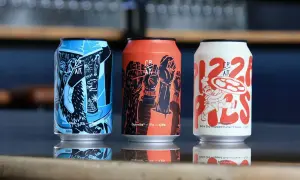 Tre lattine di crak beer con grafiche artistiche: una blu con piramide, una arancione con pugni alzati, una bianca con un pizzaiolo.