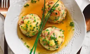 Tre canederli in brodo, guarniti con erba cipollina. Una deliziosa ricetta per un piatto tradizionale.
