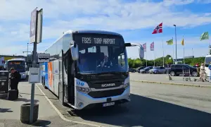 Autobus FB25 Torp Airport czeka na pasażerów. W tle parking i norweskie flagi.