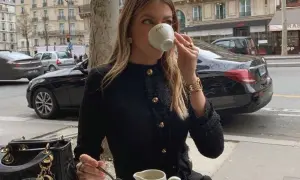Elegancka kobieta w czarnym tweedowym żakiecie, uosobienie stylu moda quiet luxury, popija kawę w paryskiej kawiarni.
