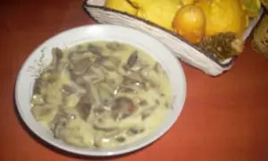 Talerz z kremowym sosem grzybowym, w tle koszyk z ozdobnymi dyniami.