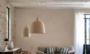 Un salon lumineux avec un mur en enduit mur interieur texturé, des suspensions en rotin, un canapé et des meubles en bois.