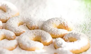 Vanillekipferl, zart und mit Puderzucker bestäubt, liegen auf einer grünen Unterlage. Ein süßer Genuss!