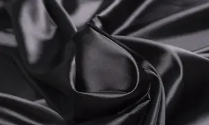 Gładka, błyszcząca satyna czarna układa się w eleganckie fałdy, tworząc wrażenie luksusu i głębi.