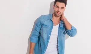 Junger Mann mit lässigem Look: blaues Jeanshemd über einem weißen Unterhemd unter T-Shirt.