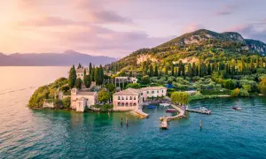 Un'isola incantevole sul gardasee westufer, con ville storiche, cipressi e ulivi, bagnata da acque turchesi al tramonto.