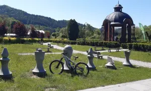 Rower czeka na przygodę na trasie w Muszynie, wśród kamiennych figur i zieleni.