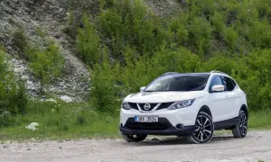Biały Nissan Qashqai J11 na drodze szutrowej, otoczony zielenią i kamienistym zboczem.