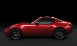 Czerwona Mazda MX-5 RF targa z czarnym dachem, zaparkowana na ciemnym tle.