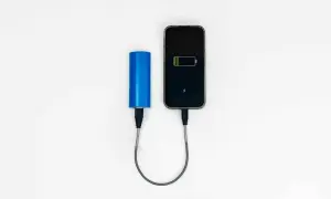 Niebieski power bank ładuje smartfon. Idealny, gdy zastanawiasz się, jaki power bank do samolotu zabrać, by mieć zawsze naładowany telefon.